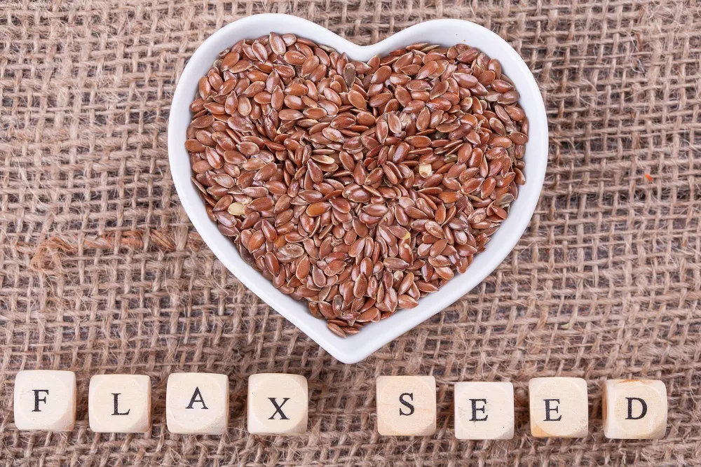 Flax seed in cup in the shape of heart on sack cloth